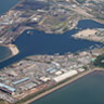 Aerial view of the Miike Port. The distinctive &quot;hummingbird&quot; form and design of the Miike Port was, and remains, a massive landform reaching out into the tidal channel of the eastern Ariake Sea. This long shape was necessary due to the tidal range of 5.5m and the consequent need to reach out into deeper water to facilitate shopping movements.